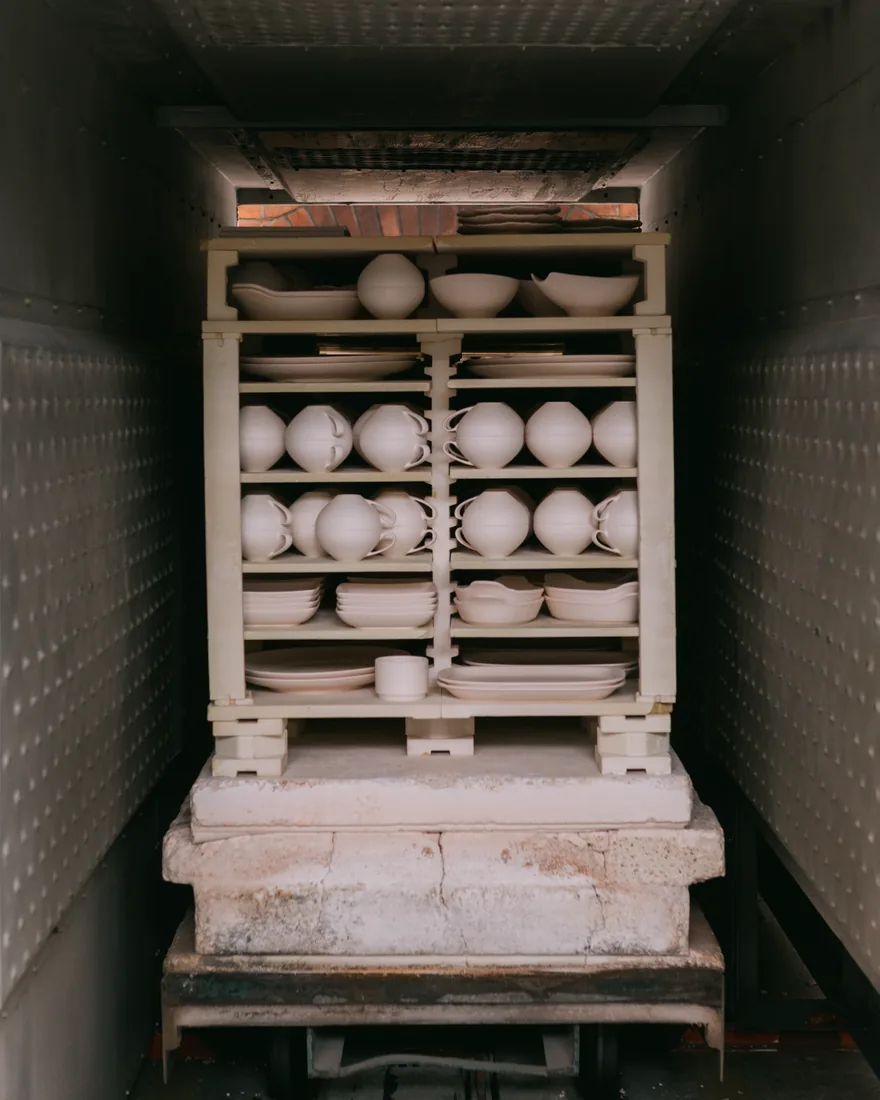 Platos de barro sin esmaltar apilados dentro de un horno cerámico, preparados para la primera cocción